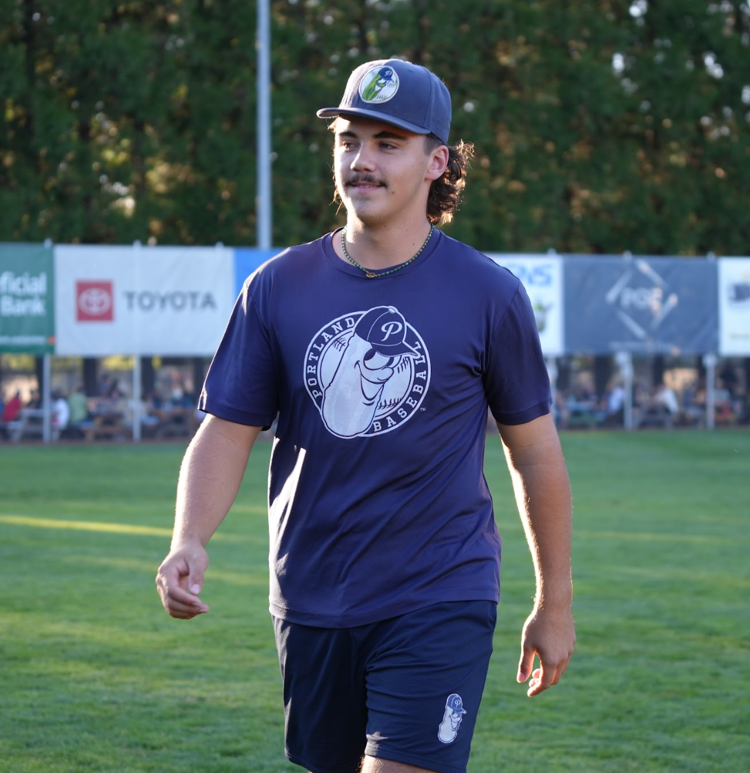 portland pickles baseball player wearing blue hat blue shirt with dillon badge and blue shorts